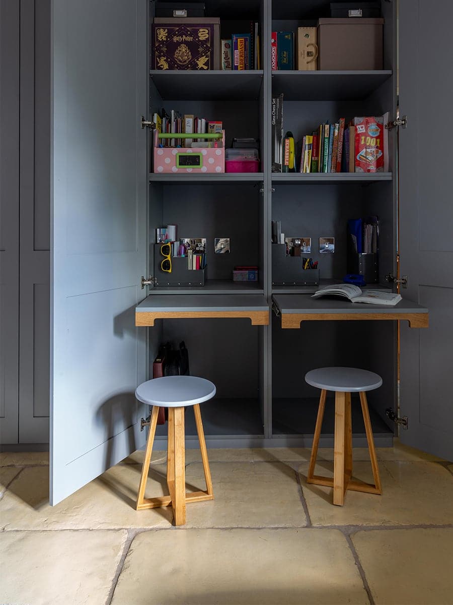 Cambray House bespoke children's homework cupboard with fold-down desks and stools on stone floor